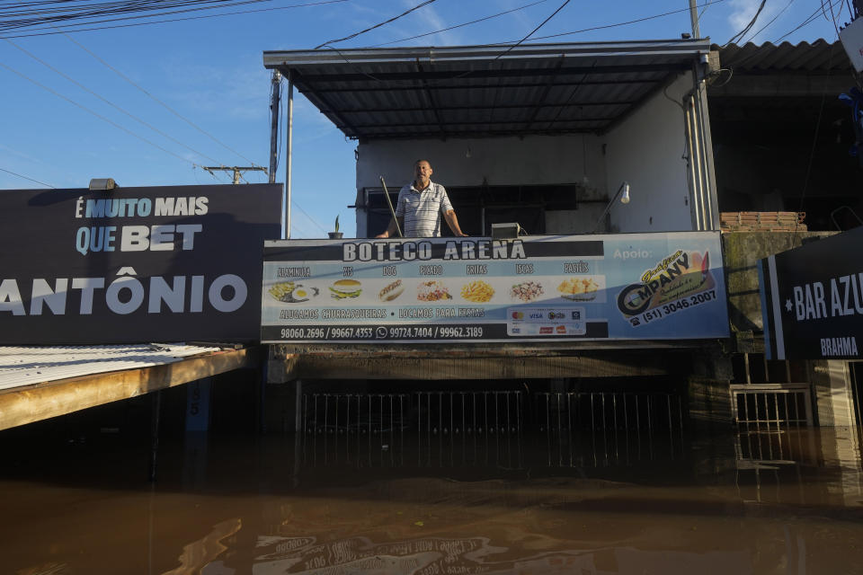 A resident stands on the balcony of his home partially submerged by flood waters from heavy rains, in Porto Alegre, Rio Grande do Sul state, Brazil, Thursday, May 9, 2024. (AP Photo/Andre Penner) is