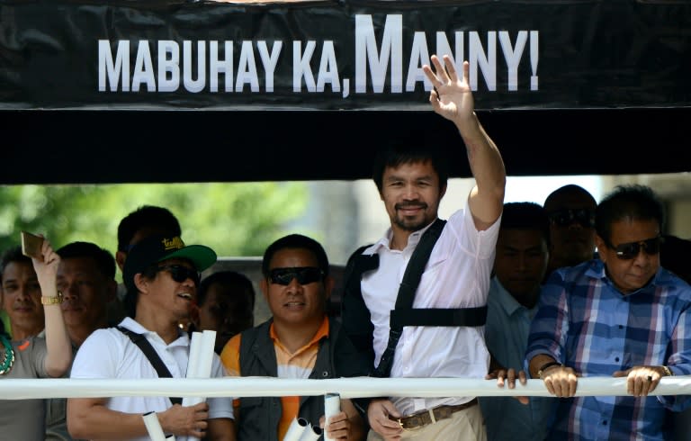 Philippine boxer Manny Pacquiao (2nd R) waves to his supporters during a welcome parade in Manila on May 13, 2015