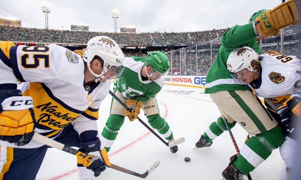 Nashville Predators' centers Matt Duchene (95) and Mikael Granlund (64) battle for the puck with Dallas Stars center Radek Faksa (12) and defenseman Jamie Oleksiak, right, in the first period of the NHL Winter Classic hockey game at the Cotton Bowl, Wednesday, Jan. 1, 2020, in Dallas. (AP Photo/Jeffrey McWhorter)