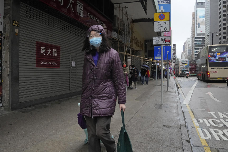 A woman wearing a protective mask walks past a closed shop in Mongkok district in Hong Kong, Thursday, Feb. 17, 2022. Hong Kong on Thursday reported 6,116 new coronavirus infections, as the city’s hospitals reached 90% capacity and quarantine facilities are at their limit, authorities said. (AP Photo/Kin Cheung)