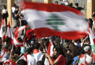 A student protester waves her national flag during protest against the government in front of the education ministry in Beirut, Lebanon, Friday, Nov. 8, 2019. Lebanese protesters are rallying outside state institutions and ministries to keep up the pressure on officials to form a new government to deal with the country's economic crisis. (AP Photo/Hussein Malla)