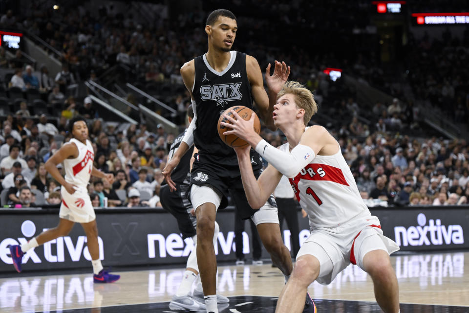 Toronto Raptors' Gradey Dick, right, drives against San Antonio Spurs' Victor Wembanyama, top, during the first half of an NBA basketball game, Sunday, Nov. 5, 2023, in San Antonio. (AP Photo/Darren Abate)