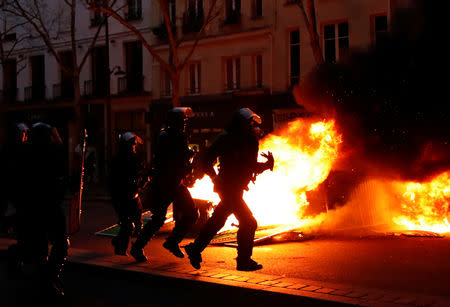 Riot policemen run near a fire during a demonstration by the "yellow vests" movement at Boulevard Saint Germain in Paris, France, January 5, 2019. REUTERS/Gonzalo Fuentes