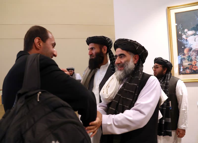 Members of Afghanistan's Taliban delegation (R) gather ahead of an agreement signing between them and U.S. officials in Doha