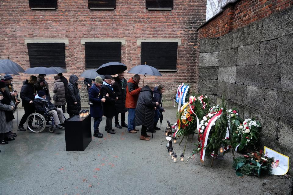 Holocaust survivors and relatives place candles next to the Death Wall in the Auschwitz Nazi death camp in Oswiecim, Poland, on Saturday, Jan. 27. Survivors of Nazi death camps marked the 79th anniversary of the liberation of the Auschwitz-Birkenau camp during World War II in a modest ceremony in southern Poland.