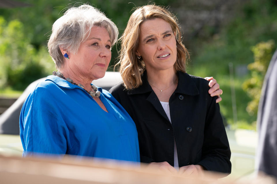 Anne Lloyd (Barbara Flynn) puts her arm around her daughter Martha (Sally Bretton) as they stand together outside in the sunshine