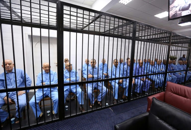 Former aides of Libyan dictator Moamer Kadhafi sit dressed in prison blue in the accused cell during their trial on July 28, 2015 at the appeals court in Tripoli