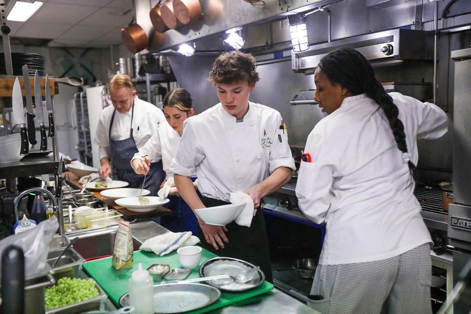 Line cook Raiden Woody prepares a plate alongside garde manger Morgan Pearson, right. In the background are sous chef Jordan Demchak and Cuisine chef-owner Paul Grosz.