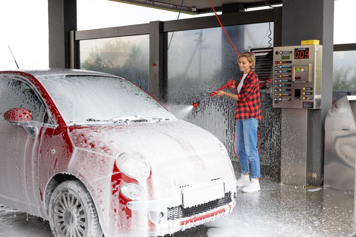 Car service. Woman working at the car wash and washing the car