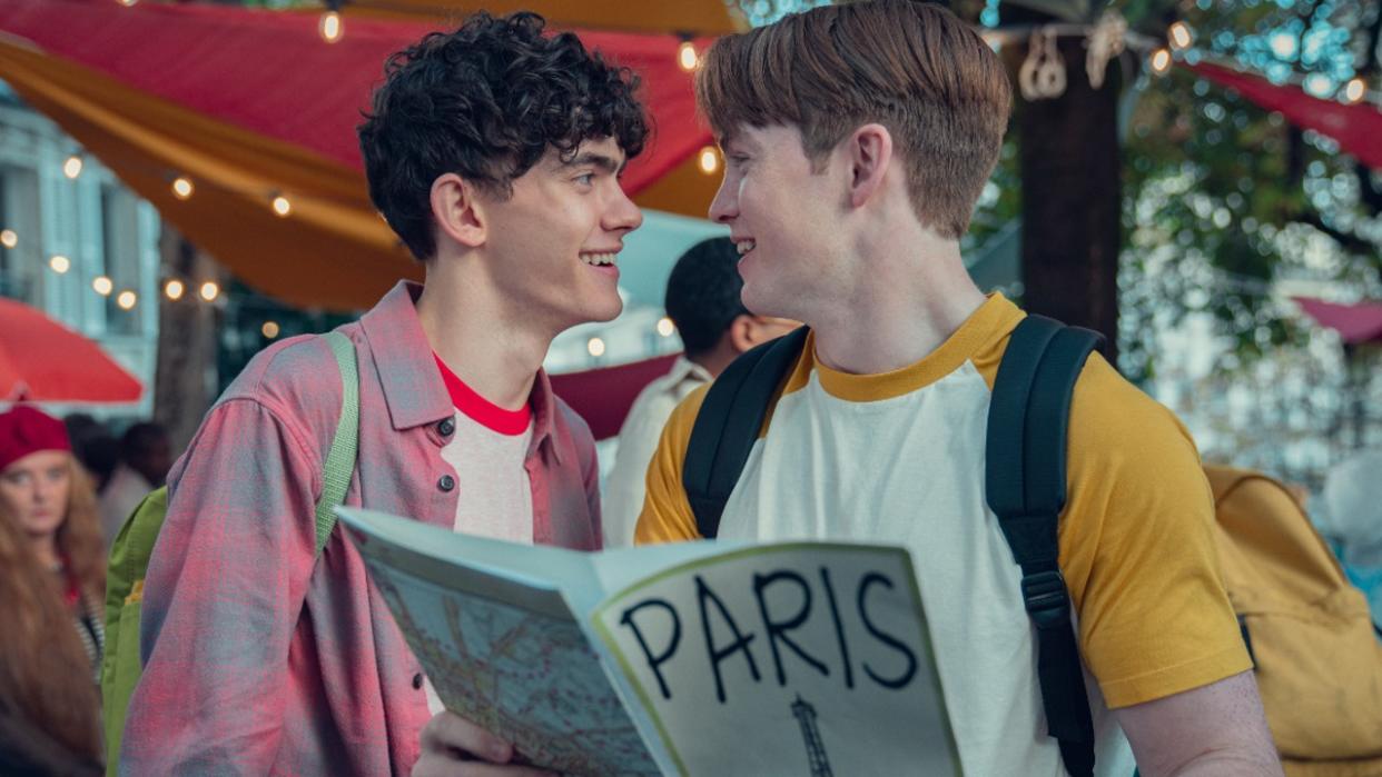  Nick and Charlie holding a Paris map and smiling at each other. . 