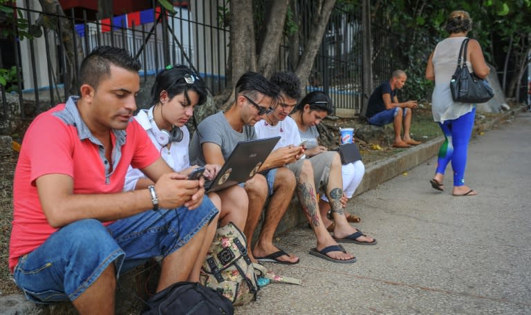 Cubans use their mobile devices to connect to the Internet via wifi in a street of Havana, on July 2, 2015