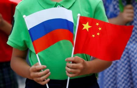 A child holds the national flags of Russia and China prior to a welcoming ceremony for Russian President Vladimir Putin outside the Great Hall of the People in Beijing, China, June 25, 2016. REUTERS/Kim Kyung-Hoon