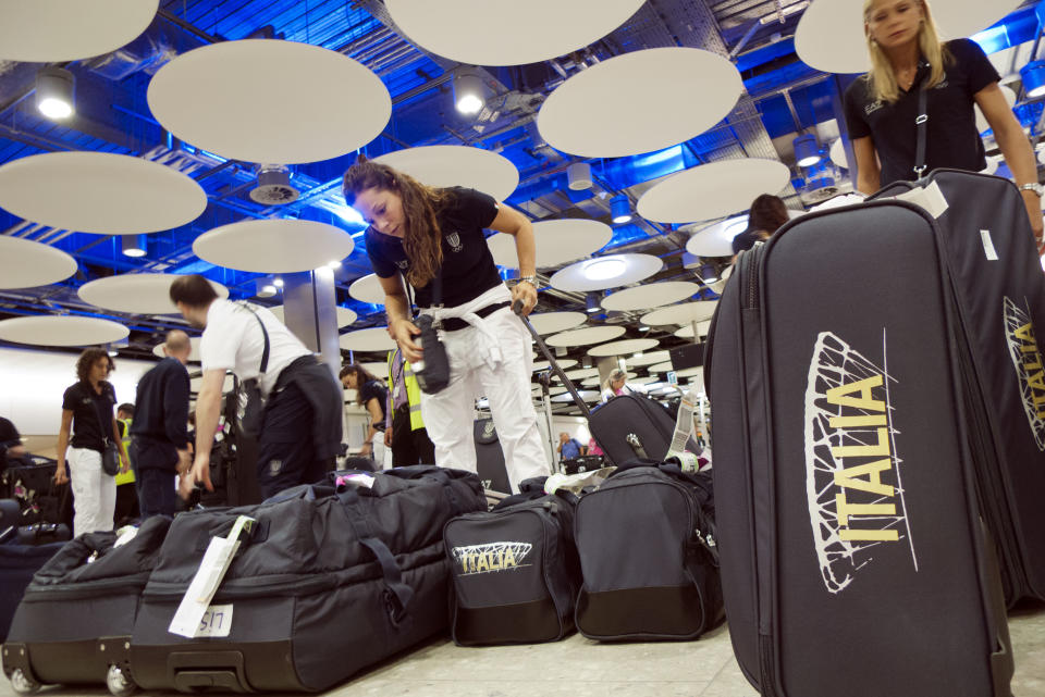 Italian women's volleyball team athletes pick up their luggage as they arrive at London's Heathrow airport to take part at the 2012 Summer Olympics, Tuesday, July 24, 2012. (AP Photo/Andrew Medichini)