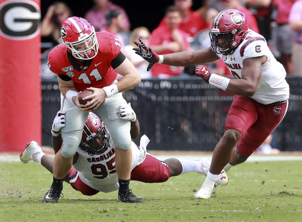 Georgia quarterback Jake Fromm is sacked by South Carolina defenders Kobe Smith, left, and D.J. Wonnum during the third quarter of an NCAA college football game, Saturday, Oct., 12, 2019, in Athens, Ga. (Curtis Compton/Atlanta Journal-Constitution via AP)