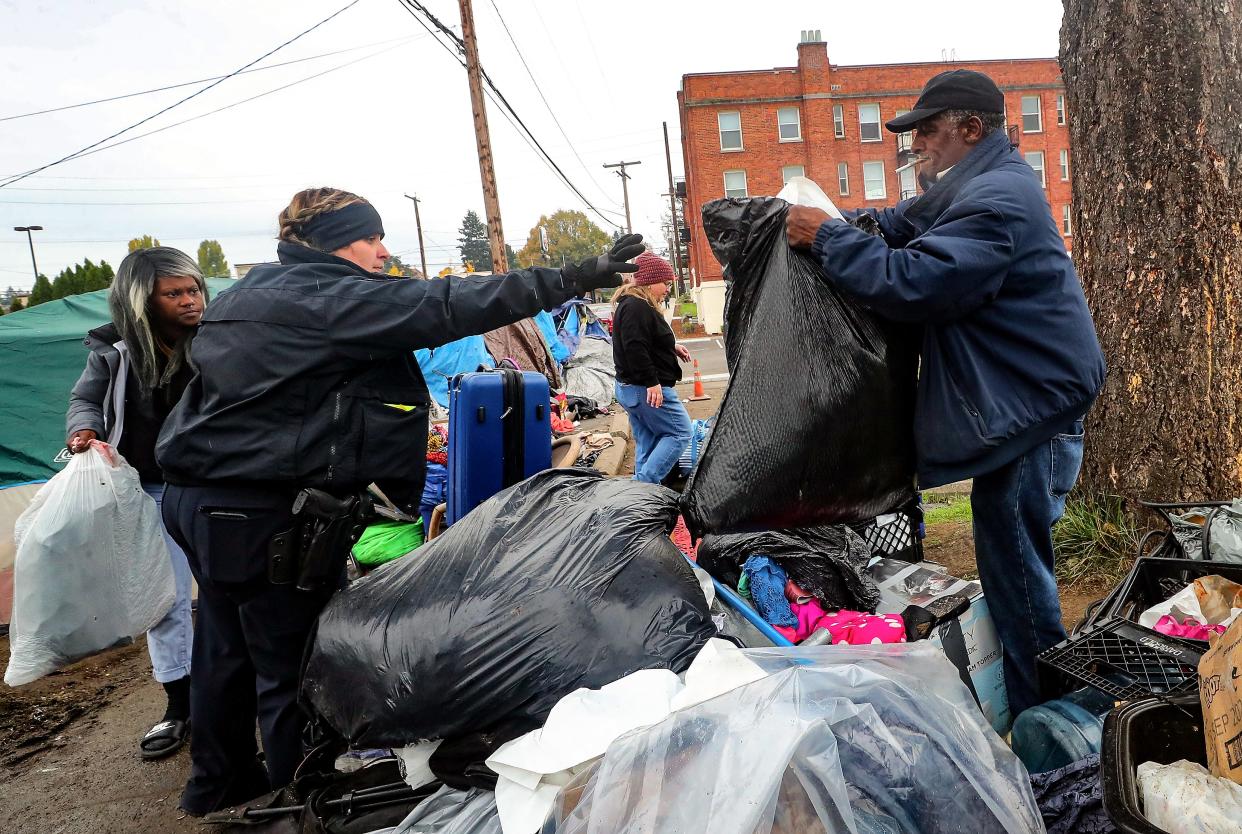 Bremerton Police Department’s Officer Hoyson reaches out to take a bag of belongings from MLK Way encampment resident Bernard (no last name given) as she helps load his stuff into a truck during a clearing of the encampment on Nov. 1. The REAL Team was able to secure a storage unit for Bernard’s things as Bremerton Homeless Community Coalition’s Kimmy Siebens, continues to try to find housing for him.