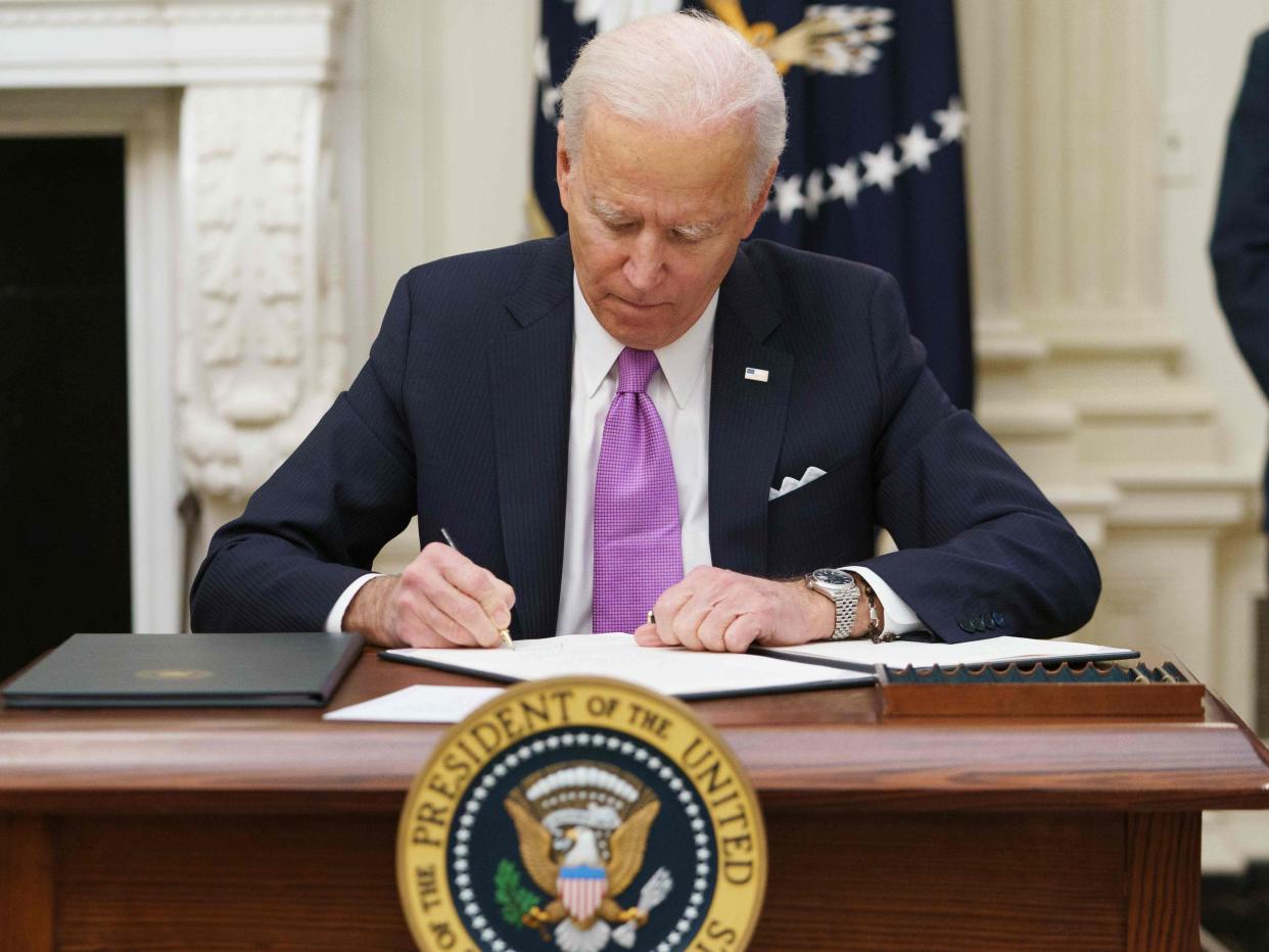 <p>Joe Biden signs executive orders as part of the Covid-19 response in the State Dining Room of the White House in Washington</p> (AFP via Getty Images)