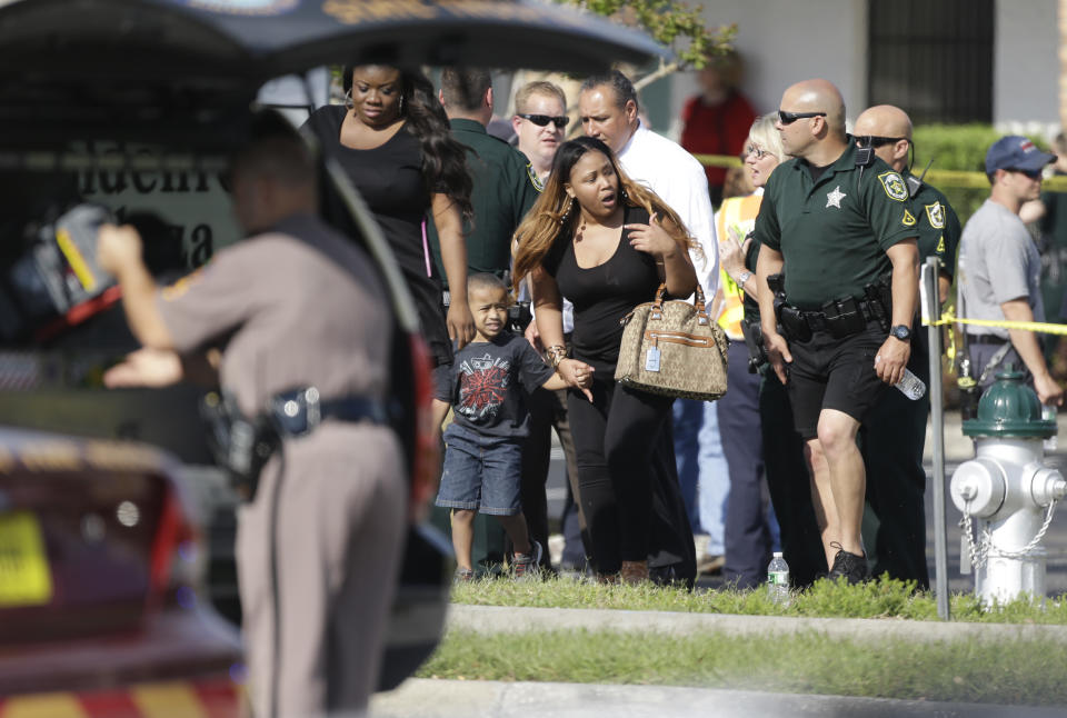 Parents with their children are escorted away with Orange County deputies after a vehicle crashed into a day care center, Wednesday, April 9, 2014, in Winter Park, Fla. At least 15 people were injured, including children. (AP Photo/John Raoux)