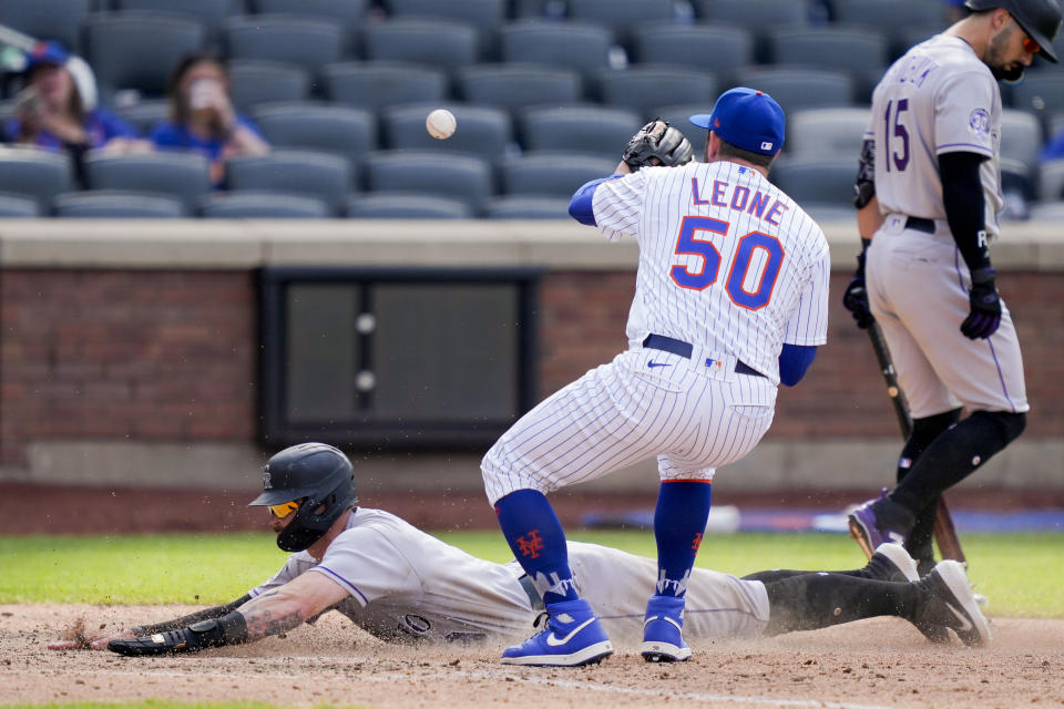 Colorado Rockies' Brenton Doyle, below, scores on a wild pitch by New York Mets relief pitcher Dominic Leone (50) in the ninth inning of a baseball game, Sunday, May 7, 2023, in New York. (AP Photo/John Minchillo)