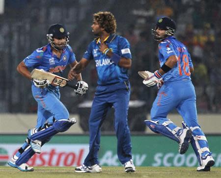 Rohit Sharma and Virat Kohli (R) run between the wickets as Sri Lanka's Lasith Malinga (C) watches during their ICC Twenty20 World Cup cricket final match at the Sher-E-Bangla National Cricket Stadium in Dhaka April 6, 2014. REUTERS/Andrew Biraj