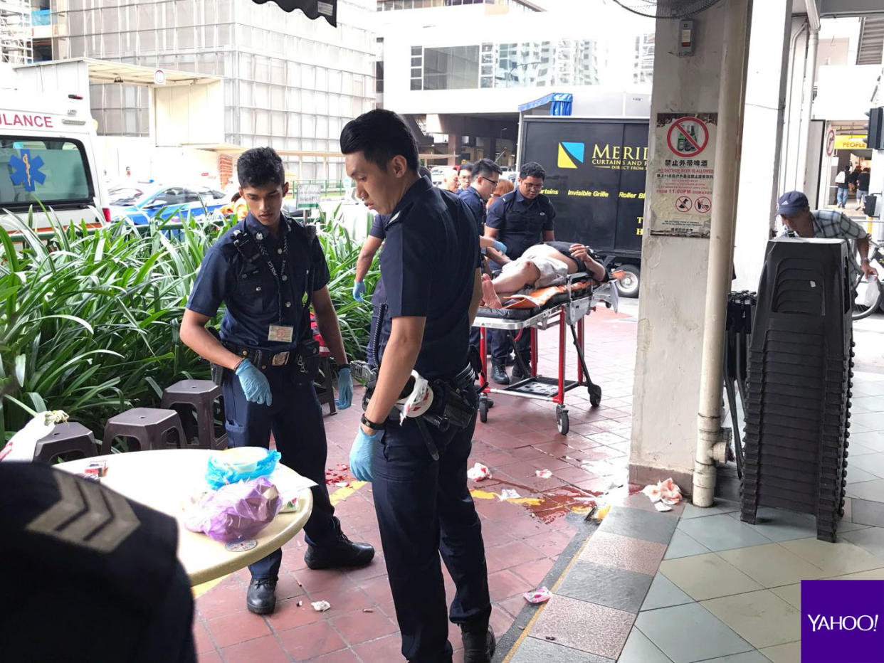 Police and the injured man seen at the S-11 coffee shop opposite the State Courts at Upper Cross Street. (PHOTO: Nigel Chin / Yahoo News Singapore)