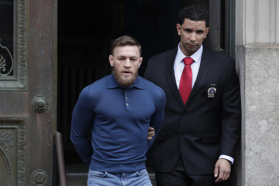 Conor McGregor is led by an official to an unmarked vehicle while leaving the 78th Precinct of the New York Police Department on April 6, 2018, in the Brooklyn borough of New York. (AP Photo)