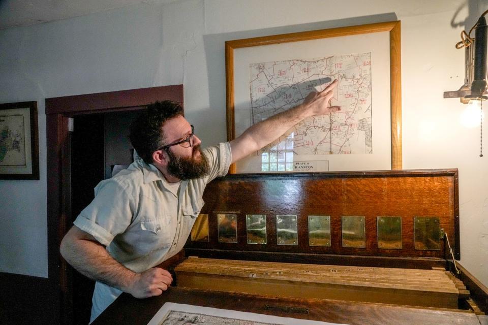 Documentarian Evan Villari with a map in his home studio in Scituate.