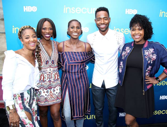 Five cast members from 'Insecure' smiling at a promotional event, in stylish casual outfits