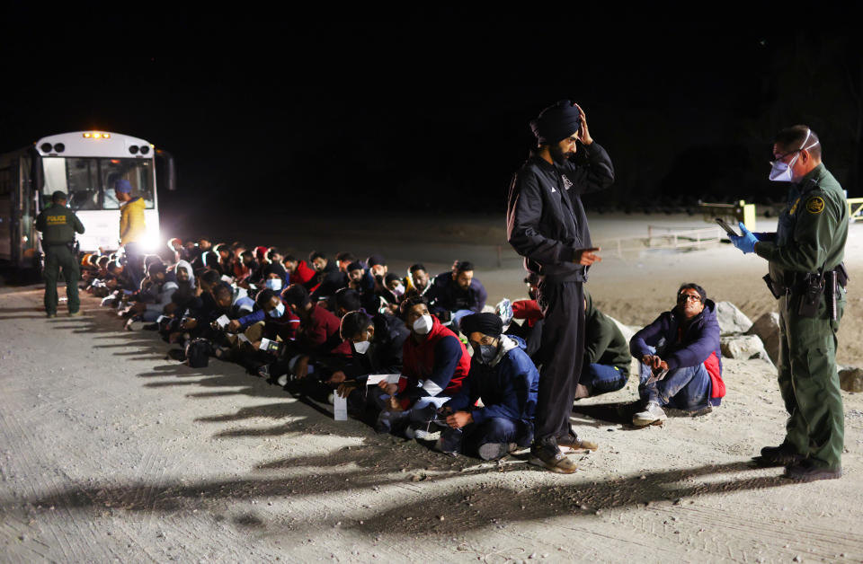 Immigrants from India wait to board a U.S. Border Patrol bus to be taken for processing after crossing the border from Mexico on May 22, 2022 in Yuma, Arizona. (Photo by Mario Tama/Getty Images)