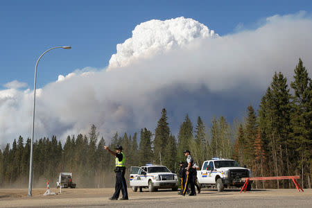 Smoke rises from nearby wildfires as police officers work a roadblock near Fort McMurray, Alberta, May 5, 2016. REUTERS/Chris Wattie