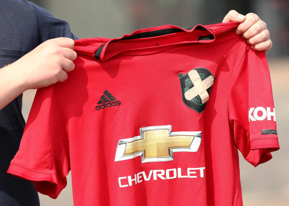 Image: A Manchester United fan holds up a football shirt with two plasters covering the club badge outside the stadium on Tuesday in Manchester, England. (Charlotte Tattersall / Getty Images)