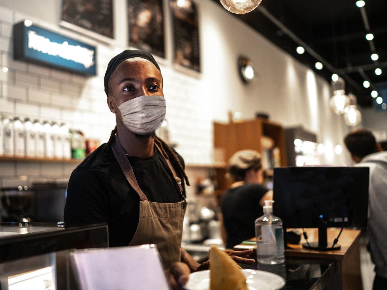 Young waiter with face mask working in coffee shop