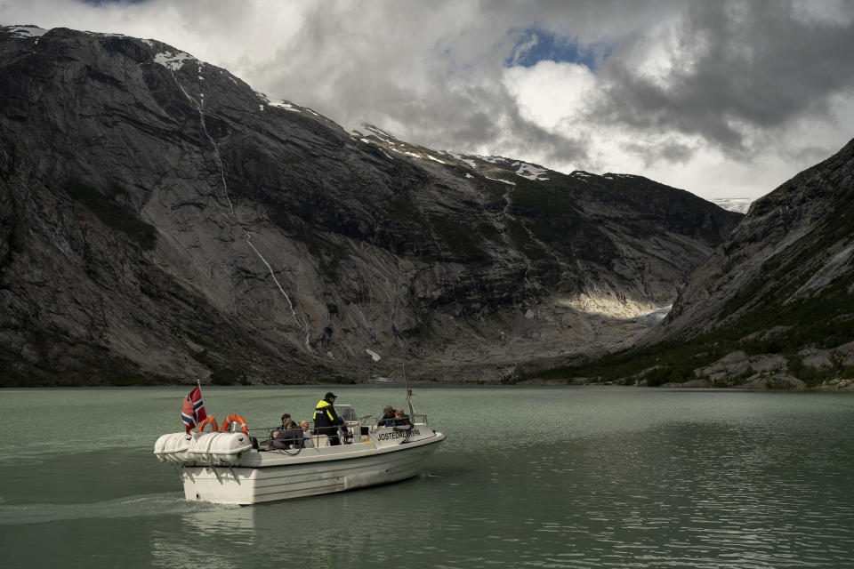 Tourists use a boat to visit the Nigardsbreen glacier in Jostedal, Norway, on Aug. 5, 2022. The Nigardsbreen glacier has lost almost 3 kilometers (1.8 miles) in length in the past century due to climate change. (AP Photo/Bram Janssen)