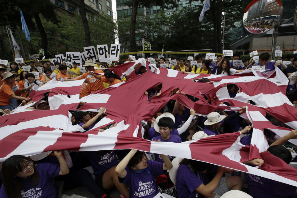 FILE - South Korean students tear a huge Japanese rising sun flag during a rally denouncing Japanese Prime Minister Shinzo Abe's statement to mark the 70th anniversary of the end of World War II, near the Japanese Embassy in Seoul, South Korea on Aug. 15, 2015. Japan’s longest-serving prime minister, Shinzo Abe was credited with instilling political and economic stability. However, he angered Japan’s neighbors South Korea and China along with many Japanese with his nationalistic rhetoric and calls to revise the country’s pacifist constitution. (AP Photo/Lee Jin-man, File)