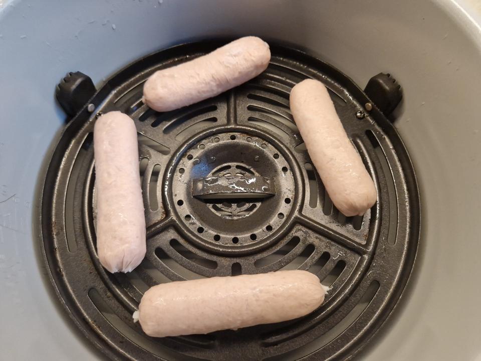 four frozen sausage links arranged in an air fryer