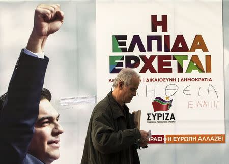 A man walks near a banner with an image of opposition leader and head of radical leftist Syriza party Alexis Tsipras at the party's pre-elections kiosk in Athens January 21, 2015. REUTERS/Marko Djurica