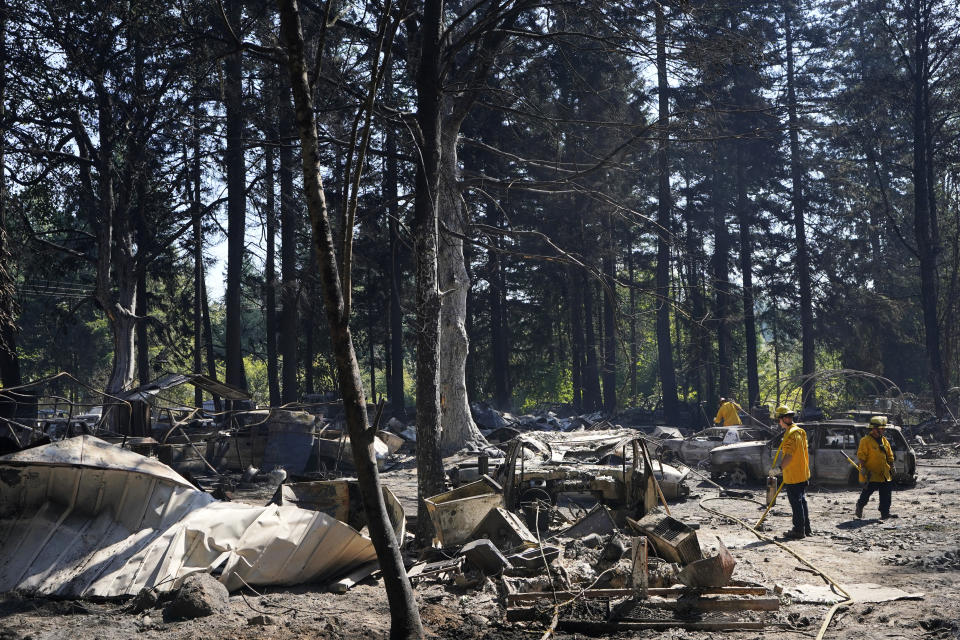 Firefighters work to put out hotspots, Tuesday, Sept. 8, 2020, after a wildfire destroyed homes and outbuildings in Graham, Wash., overnight south of Seattle. (AP Photo/Ted S. Warren)