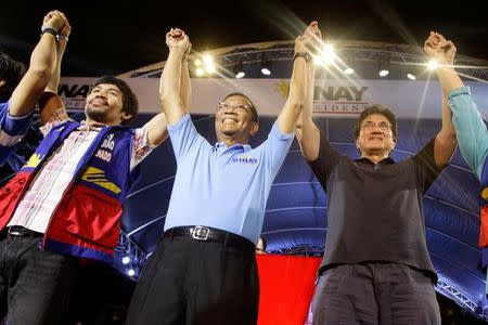 Philippine presidential candidate and vice-president Jejomar Binay (C) with his running mate senator Gringo Honasan (R) and senatorial candidate Manny Pacquiao raise their hands during the last campaign rally before the national election in Makati city, metro Manila May 7, 2016. REUTERS/Czar Dancel