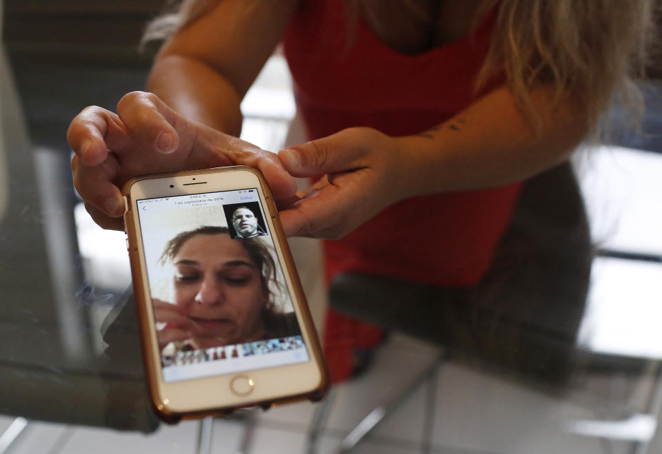 In this Aug. 6, 2019, photo, Barbara Rodriguez shows a photograph on her phone of her talking to her husband, Pablo Sanchez at her home in Hialeah, Fla. After seeking asylum in the United States at the Mexican border, Sanchez ended up in a detention center facing what has become an increasingly common scenario under President Donald Trump: deportation to Cuba. (AP Photo/Brynn Anderson)