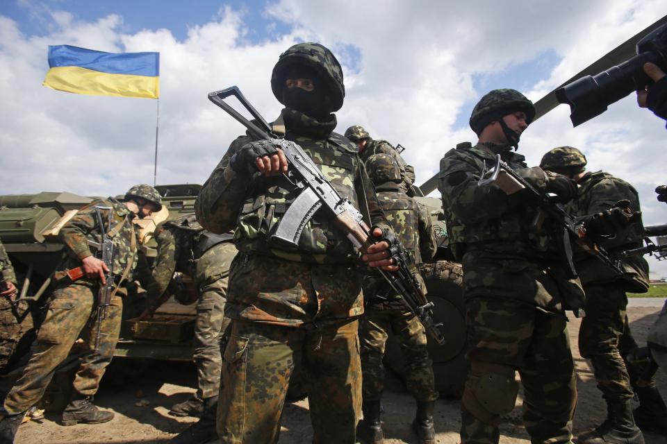 Ukrainian Army troops receive munitions at a field on the outskirts of Izyum, Eastern Ukraine, Tuesday, April 15, 2014. An Associated Press reporter saw at least 14 armored personnel carriers with Ukrainian flags, one helicopter and military trucks parked 40 kilometers (24 miles) north of the city on Tuesday. (AP Photo/Sergei Grits)