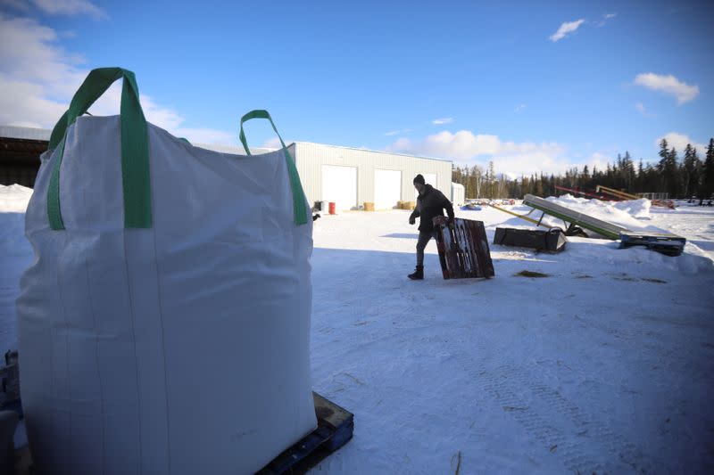 Yukon Grain Farm employee Jake Loos drags a pallet past bags of feed at the Yukon Grain Farm near Whitehorse