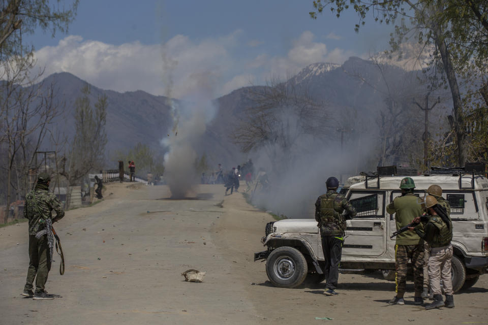 Indian policemen fire teargas shells at Kashmiri villagers as they throw stones and bricks at them during a protest near the site of a gunbattle in Pulwama, south of Srinagar, Indian controlled Kashmir, Friday, April 2, 2021. Anti-India protests and clashes have erupted between government forces and locals who thronged a village in disputed Kashmir following a gunbattle that killed three suspected militants. Police say the gunfight on Friday erupted shortly after scores of counterinsurgency police and soldiers launched an operation based on tip about presence of militants in a village in southern Pulwama district. (AP Photo/ Dar Yasin)