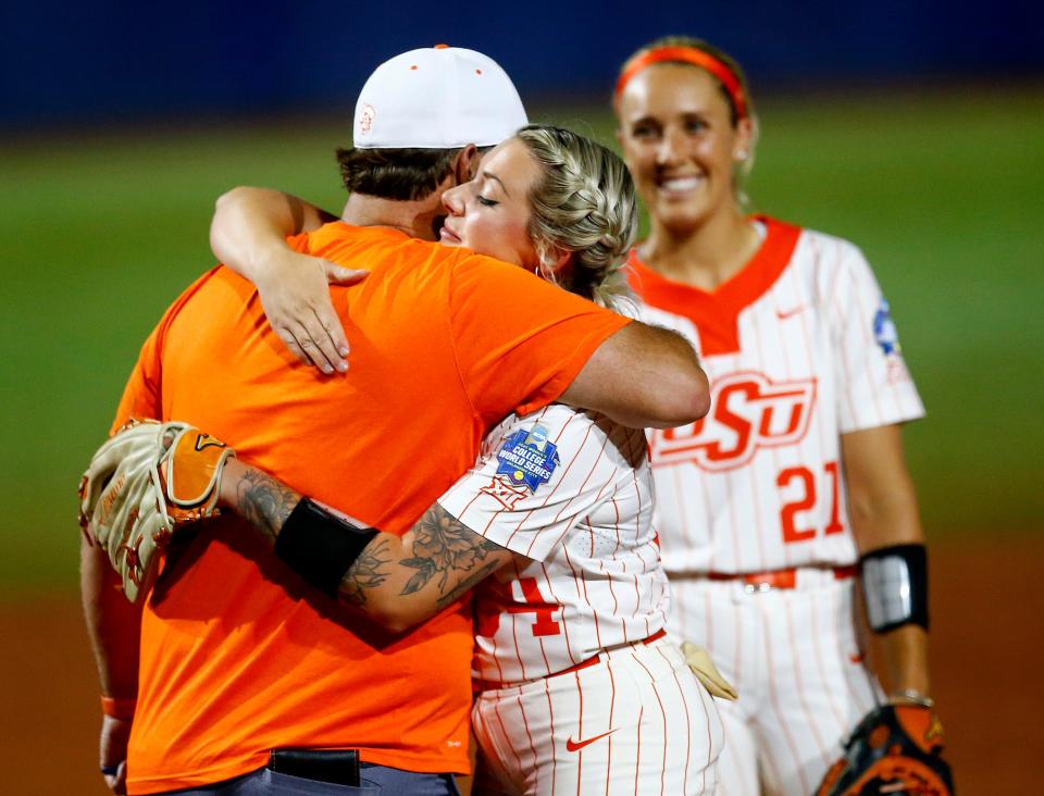 Oklahoma State head coach Kenny Gajewski hugs Logan Simunek (34) after taking her out of the game in the seventh inning  Women's College World Series softball game between Oklahoma State and Florida State at the USA Softball Hall of Fame Stadium in Oklahoma City, Sunday, June 6, 2021. Florida State won 4-2.