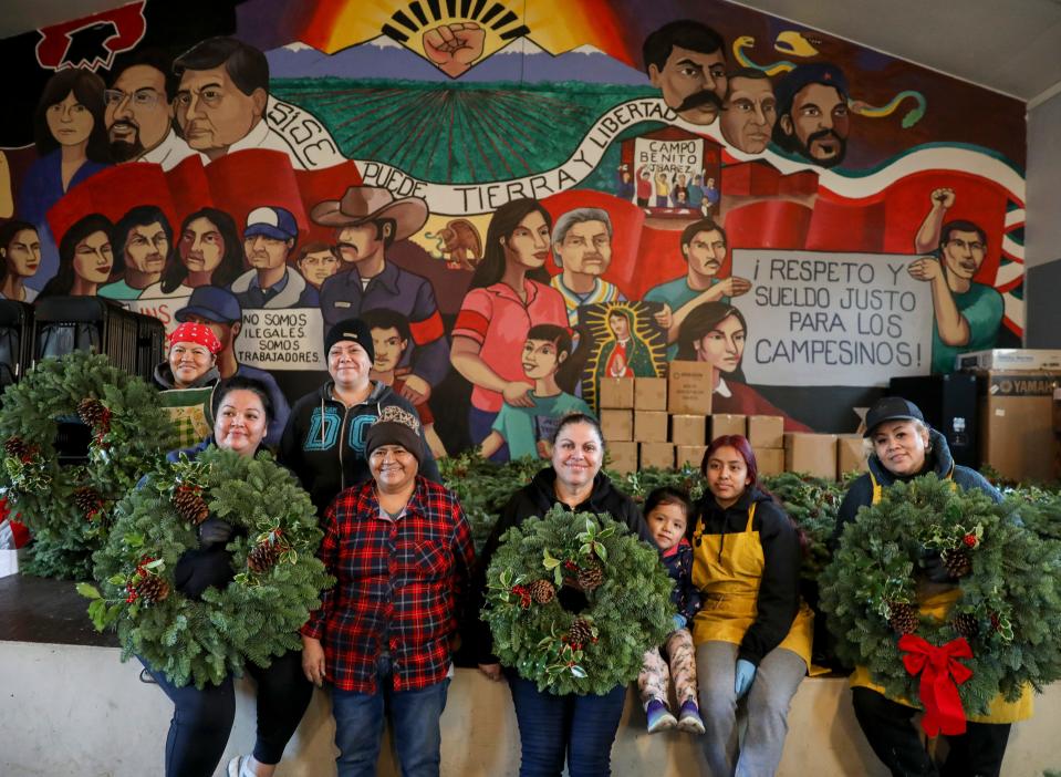 Women with MLP hold Christmas wreaths made for their annual drive.