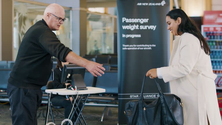 En esta foto proporcionada por Air New Zealand, una mujer entrega su maleta a un miembro del personal para ser pesada antes de un vuelo en Auckland, Nueva Zelanda, el 29 de mayo de 2023.