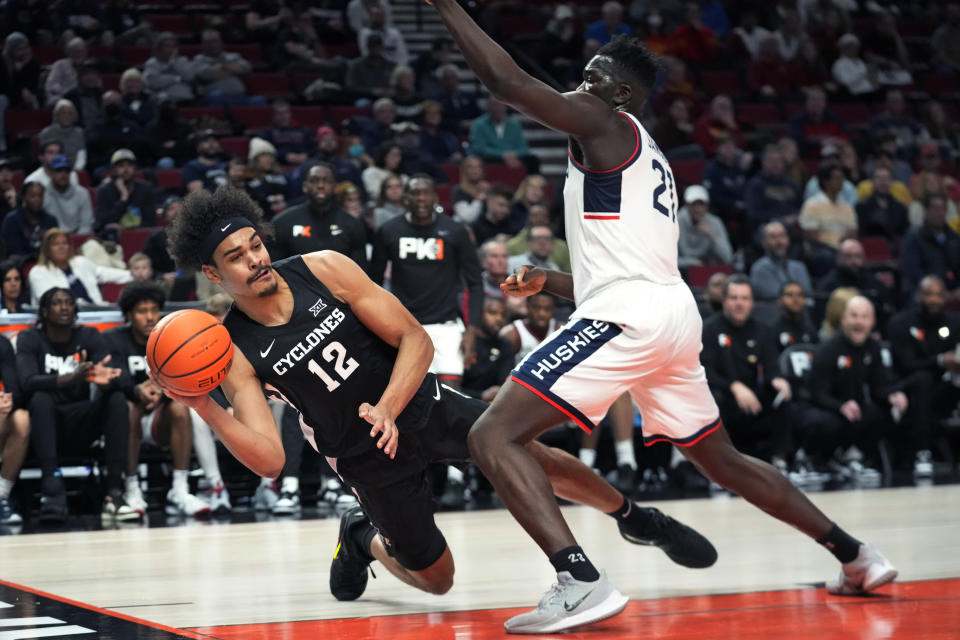 Iowa State forward Robert Jones (12) passes the ball as Connecticut forward Adama Sanogo (21) defends during the first half of an NCAA college basketball game for the championship of thePhil Knight Invitational on Sunday, Nov. 27, 2022, in Portland, Ore. (AP Photo/Rick Bowmer)