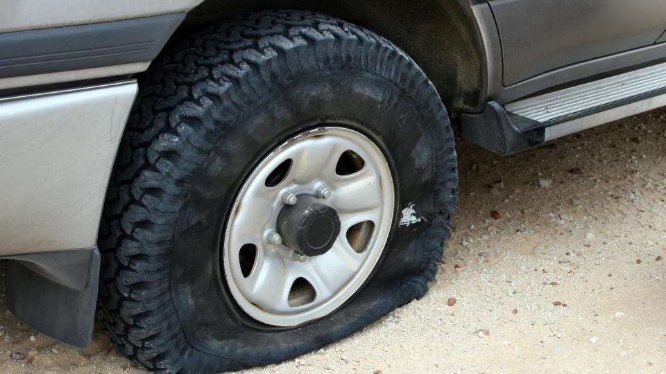 A flat tire deflating on an unpaved road