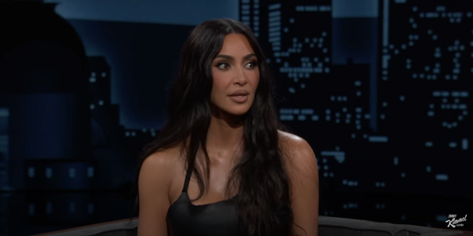 Kim Kardashian in a sleek top, seated on a TV show set