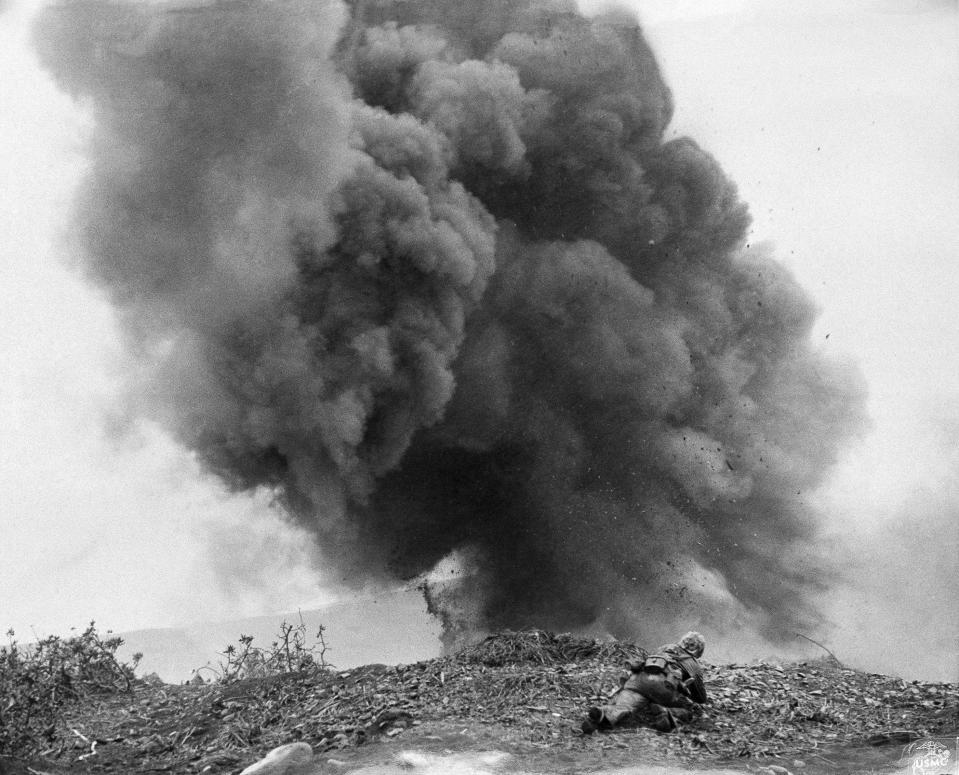 A Marine demolitions man hugs the ground to escape flying debris after setting off a high-explosive charge to blast a Japanese pillbox on Iwo Jima on March 2, 1945. After their capture, many Japanese positions had to be destroyed lest the enemy return to the shelters and fire on Marine flanks.