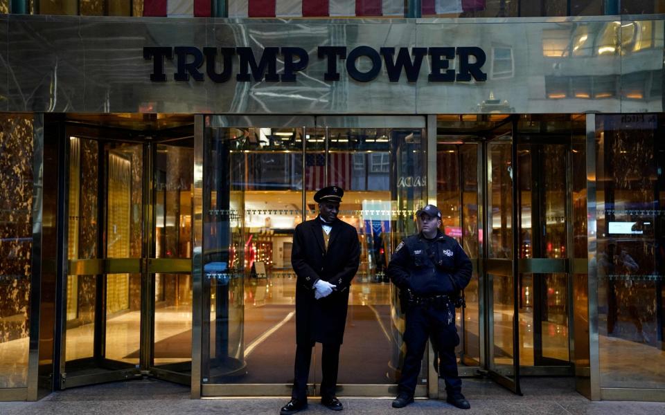 A police officer and a building employee stand in front of Trump Tower in New York following the development - AFP