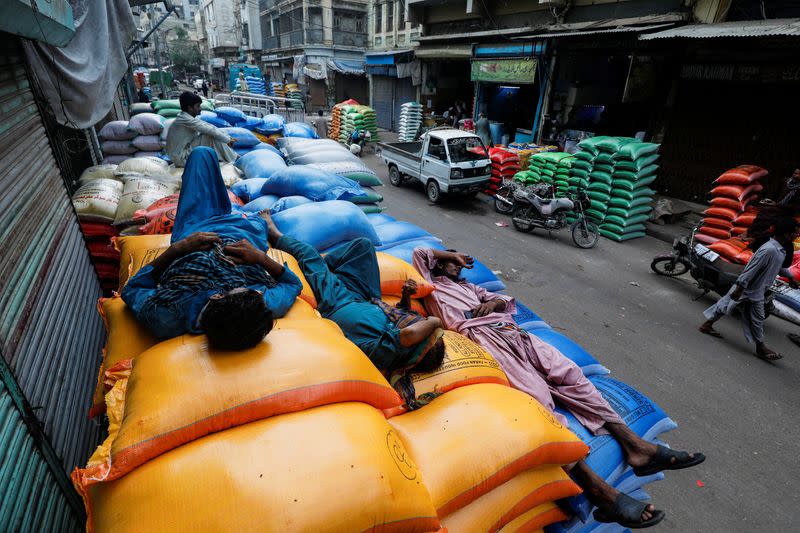 Labourers take nap on the sacks of grains and sugar outside shops at the wholesale grain market in Karachi
